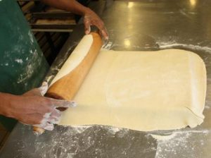 Kitchen staff preparing dough by hand